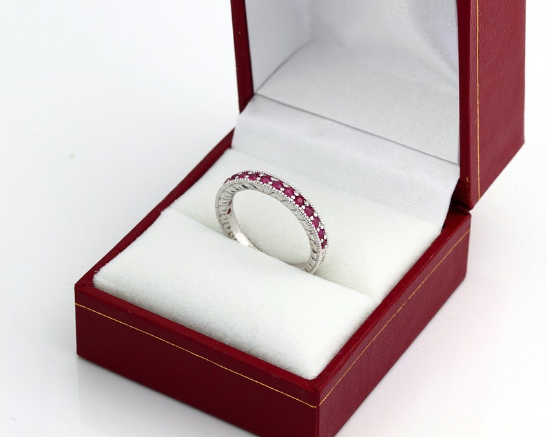 May include: A white gold band ring with a row of ruby gemstones set in the band.
