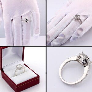 May include: A silver engagement ring with a large, round, clear center stone surrounded by smaller stones. The ring is on a white background.