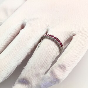 May include: A silver band ring with a row of red ruby stones.