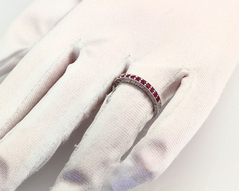 May include: A silver band ring with a row of red ruby stones.