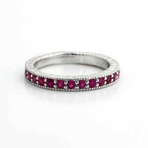 May include: A silver band ring with a row of small, red ruby stones set in the center.