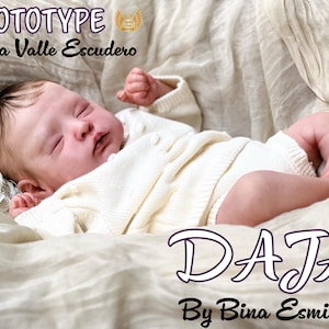 Może przedstawiać: Realistyczna lalka niemowlęca, ubrana w biały strój, leżąca na kremowym kocu. Imię lalki, "DAJA", jest napisane fioletową czcionką. Widoczny jest również tekst "Prototype Maria Valle Escudero".