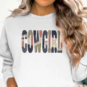 Puede incluir: Sudadera blanca con la palabra "COWGIRL" en un diseño de patchwork. Las letras están hechas de mezclilla, cuadros y encaje. Una parte superior casual y cómoda.