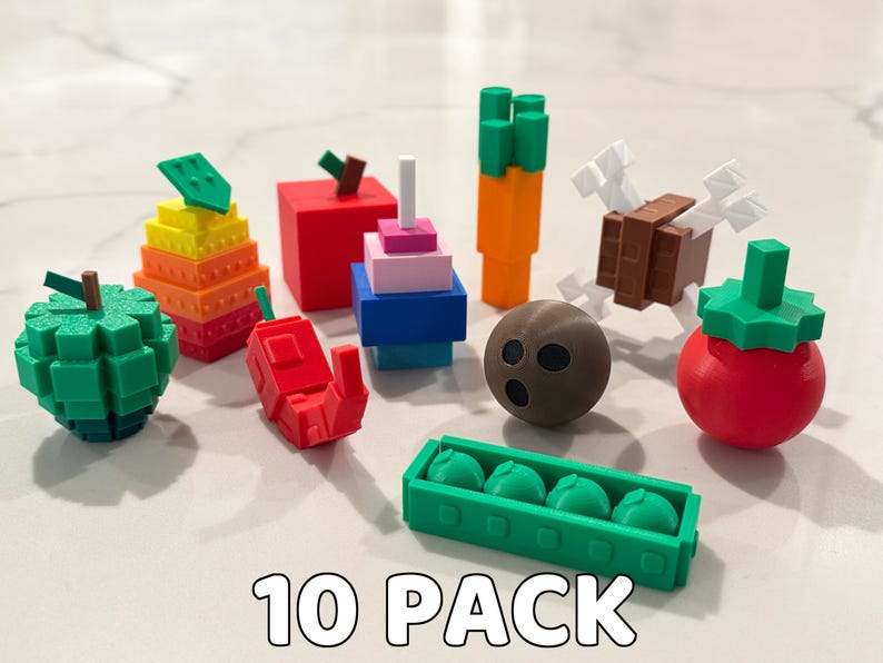 Op de afbeelding: Een verzameling van tien kleurrijke, geometrische voedselminiaturen. Inclusief een groene appel, een rode peper, een wortel, een tomaat, een kokosnoot en een bakje groene erwten. De tekst "10 PACK" staat onderaan.