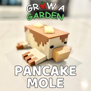 May include: A whimsical, blocky Pancake Mole figure with a pancake-shaped body, brown and tan details, and a square of butter on top. The text "GROW A GARDEN" and "PANCAKE MOLE" are displayed above and below the figure.