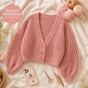 Peut inclure: Un cardigan rose en crochet avec un col en V, des manches longues et des boutons en bois. L'image comprend un téléphone, des ciseaux et de la laine. Le texte sur l'image indique "TÉLÉCHARGEMENT INSTANTANÉ" et "OFFRE TÉLÉPHONE MIGNON".