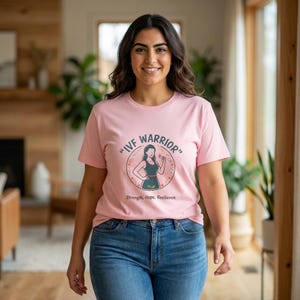 Peut inclure: T-shirt rose clair avec l'inscription "IVF Warrior" dans un cercle. Le motif comprend une illustration de femme et les mots "Force, Espoir, Résilience". La personne porte un jean bleu.