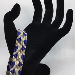 May include: A blue and silver beaded bracelet with a geometric pattern.