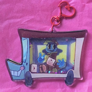 May include: A clear acrylic keychain featuring a cartoon mail truck design with a blue character holding letters. The keychain has a red heart-shaped clasp and is set against a pink background.