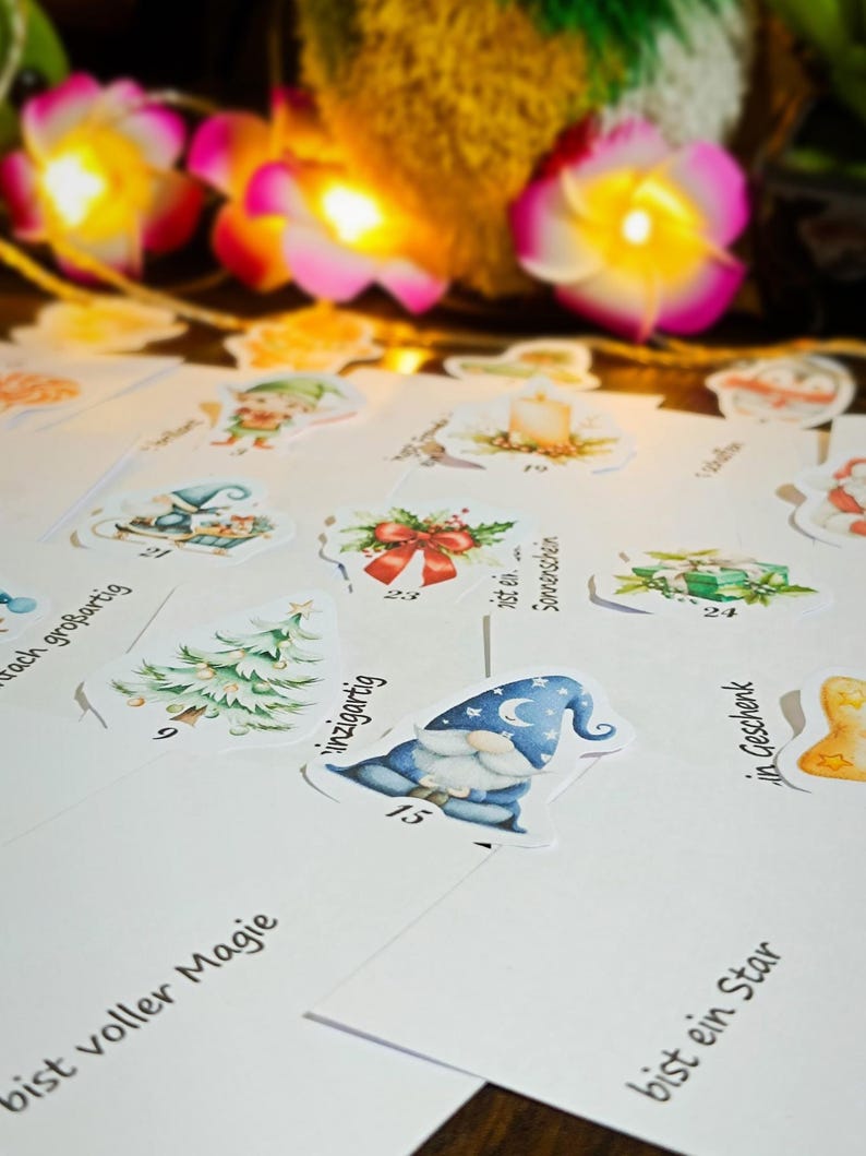 Puede incluir: Una colecci&oacute;n de pegatinas y tarjetas ilustradas con tem&aacute;tica navide&ntilde;a. Las pegatinas presentan dise&ntilde;os festivos como un gnomo, un &aacute;rbol de Navidad y regalos. Las tarjetas tienen frases como "Eres una estrella" y "Lleno de magia".
