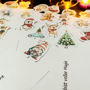May include: A collection of Christmas-themed stickers featuring festive illustrations. Designs include a penguin, reindeer, Christmas tree, gingerbread man, and a gnome. The stickers are on a white surface, with some text visible.