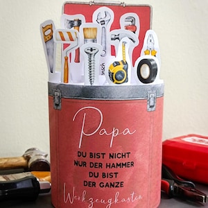 May include: A red toolbox-shaped card with a gray top and a collection of tool illustrations. The card reads "Papa" and "DU BIST NICHT NUR DER HAMMER DU BIST DER GANZE Werkzeugkasten" in white script. A hammer and other tools are visible.