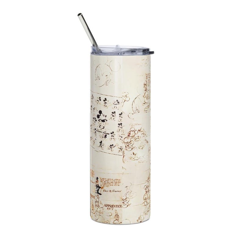 May include: A tall, cylindrical stainless steel tumbler with a clear plastic lid and a metal straw. The exterior features a cream-colored background with brown sketches of Mickey Mouse in various poses, along with the text Mickey Mouse and Apprentice RX-1.