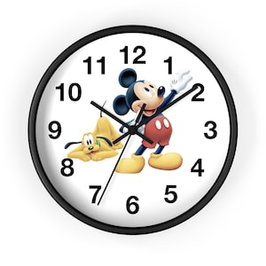 以下が含まれることがあります： 黒いフレームと白い文字盤の丸い壁掛け時計。ミッキーマウスとプルートの漫画のキャラクターが描かれています。ミッキーは手を振っており、プルートは横になっています。黒い数字で時間が示されています。