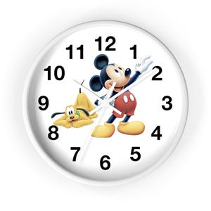 May include: White wall clock featuring Mickey Mouse and Pluto. Mickey is in a classic pose, wearing red shorts, yellow shoes, and white gloves. Pluto is lying down. Black numbers mark the hours on the white clock face.