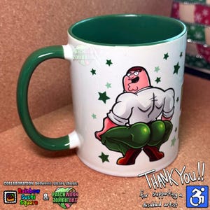 May include: White ceramic mug with a green interior and handle. The mug features a cartoon illustration of a character in a white shirt and green trousers. Green star shapes are scattered around the character. Text on the mug reads "Thank You!!" and "for Supporting a disabled artist."