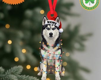 May include: A Christmas ornament featuring a Siberian Husky wearing a Santa hat with the word "NAME" on it, and wrapped in colorful Christmas lights. The ornament has a red ribbon for hanging and the words "CUSTOM NAME" on a starburst.