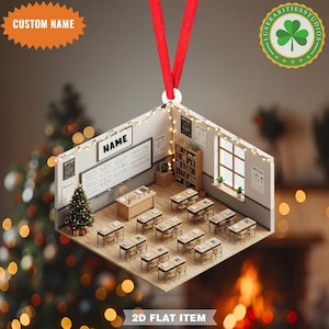 May include: A 2D flat classroom ornament with a red ribbon for hanging. The miniature classroom features desks, a chalkboard with the name "NAME", a Christmas tree, and string lights. The ornament has the text "CUSTOM NAME" and "2D FLAT ITEM".