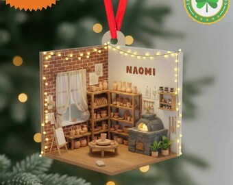 May include: A personalized ornament featuring a miniature pottery studio scene. The ornament includes a brick wall, shelves filled with pottery, and the name "NAOMI". The ornament is a 2D flat item with a red ribbon for hanging.
