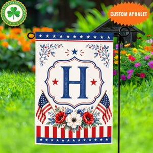 May include: A patriotic garden flag featuring the letter "H" in navy blue, surrounded by red stars and floral accents. Two American flags flank a floral arrangement of red, white, and blue flowers. The top and bottom borders have stars.