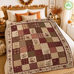 Pode incluir: Uma colcha de retalhos com uma grade de quadrados em tons de bordô, creme, verde-oliva e castanho. Os quadrados exibem vários padrões florais e designs xadrez, emoldurados por uma borda larga com um motivo repetitivo de videira floral.