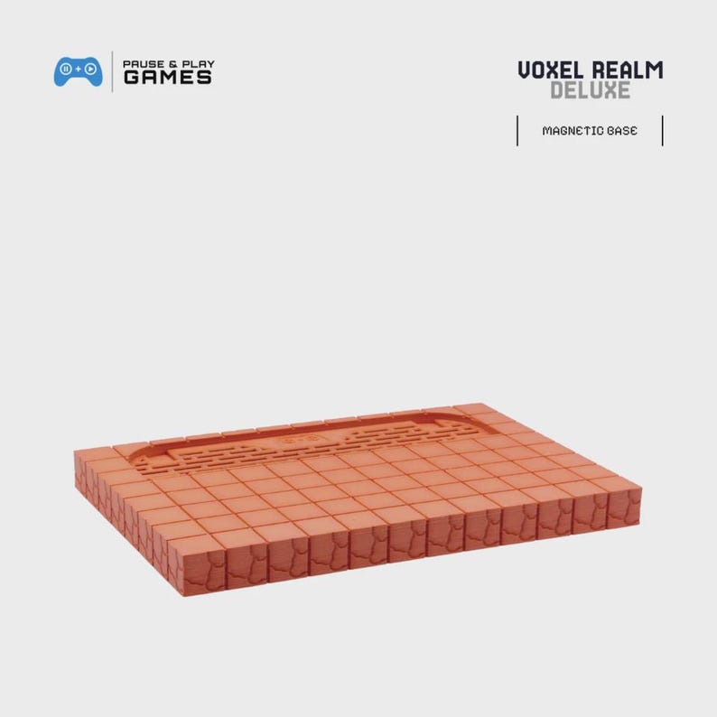 May include: A rectangular, terracotta-colored game base with a grid pattern and a recessed area. The product is labeled "VOXEL REALM DELUXE" with "MAGNETIC BASE" below. The logo for "PAUSE & PLAY GAMES" is in the upper left corner.