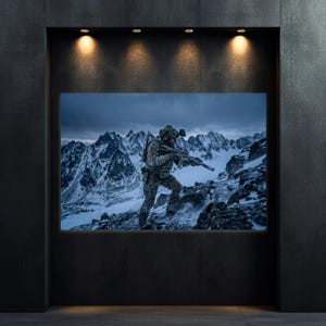 May include: A framed print of a soldier in camouflage gear traversing a snowy mountain range. The soldier is holding a rifle and is equipped with tactical gear. The background features snow-covered peaks under a cloudy sky. The print is displayed in a dark, recessed wall.