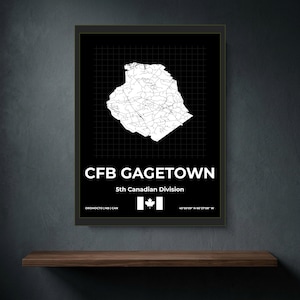 May include: A framed black and white map print of CFB Gagetown featuring a white road network on a black background with a grid overlay. Text reads CFB GAGETOWN, 5th Canadian Division, Oromocto | NB | CAN, and coordinates 45°50'09" N 66°27'08" W.