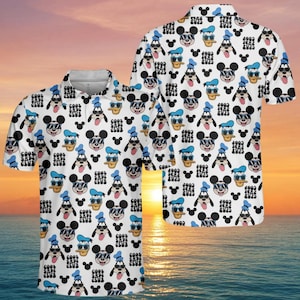 Könnte beinhalten: Weißes Poloshirt mit einem sich wiederholenden Muster von Mickey Mouse, Donald Duck und Goofy mit Sonnenbrillen und Hüten. Das Shirt hat auch den Text "COOL DADS CLUB" in Schwarz. Das Shirt ist kurzärmlig und hat einen Kragen.