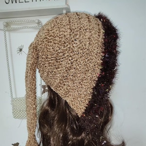 Può includere: Un cappello all'uncinetto fatto a mano di colore marrone chiaro con una lunga estensione a punta. Il cappello presenta un bordo soffice marrone scuro lungo il bordo. Il cappello è progettato per essere indossato sulla testa.