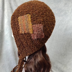 Handgemaakte bruine gehaakte hoed met oorklep: patchworkaccenten, gezellige winterhoofddeksels.