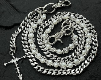 May include: Silver-toned chain with a cross pendant and faux pearl accents. The chain features a curb link design and lobster clasp closures. The cross pendant has a detailed, spiky design.