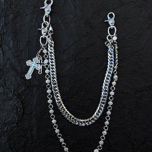 Puede incluir: Accesorio de cadena plateada con dos cierres y múltiples estilos de cadena. Un colgante de cruz cuelga del cierre superior. Las cadenas incluyen una cadena de eslabones, una cadena de cuentas y una cadena más pequeña con un colgante de cruz. Diseñado para sujetarse a una trabilla del cinturón.