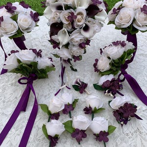 May include: A wedding bouquet set with white roses, calla lilies, and purple hydrangeas. The set includes a bridal bouquet, bridesmaids bouquets, boutonnieres, and corsages.