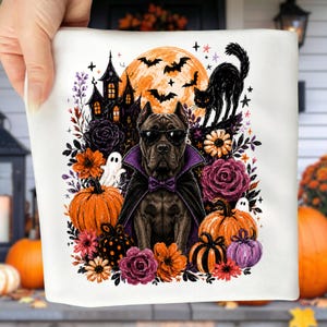 May include: A white fabric square featuring a graphic print of a dog wearing sunglasses and a purple-lined black cape. The scene includes a haunted house, a full orange moon, bats, a black cat, pumpkins, ghosts, and purple and orange flowers.