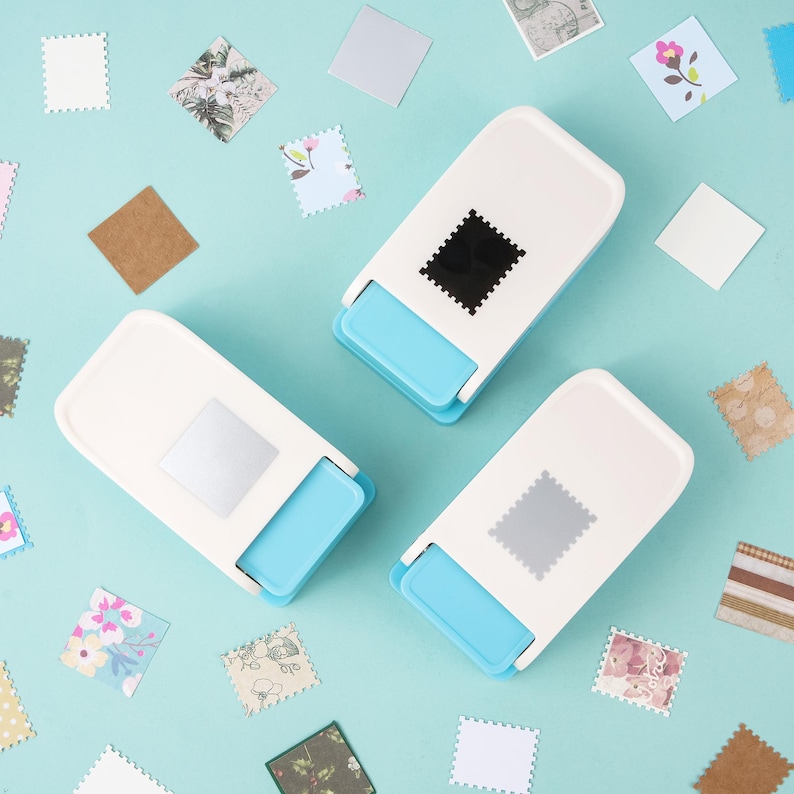 May include: Three white and blue stamp-shaped paper punches with a square stamp design. Scattered around are various patterned square paper cutouts in floral, geometric, and solid colors. The background is a light blue.