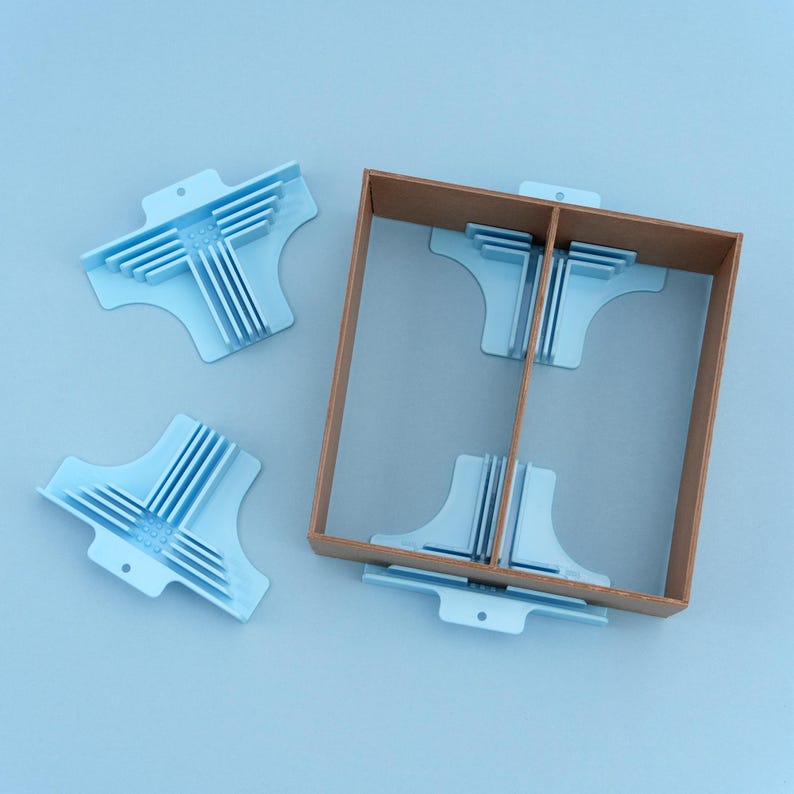 May include: A light blue box joint jig with several matching jigs. The jigs are made of plastic and are designed to help create strong and accurate box joints. The box joint jig is placed inside a brown wooden box.