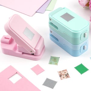 May include: A set of four plastic paper punches in pastel pink, mint green, and light blue. Each punch features a square-shaped design with scalloped edges. Several small, square paper cutouts with scalloped borders are scattered nearby.