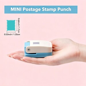 May include: A mini postage stamp punch in blue and white, held in a hand. The punch is 0.53 inches wide and 0.66 inches tall. The text "MINI Postage Stamp Punch" is displayed above the punch.