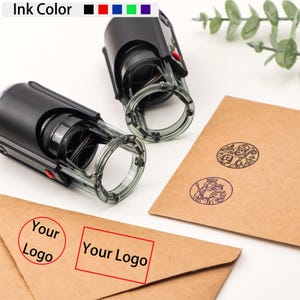 Op de afbeelding: Twee zwarte zelfinktende stempels met doorzichtige handgrepen en rode knoppen worden getoond. De afbeelding toont bruine enveloppen met gestempelde ontwerpen en de tekst "Your Logo" in een cirkel en een rechthoek. Kleuropties voor inkt worden bovenaan weergegeven.