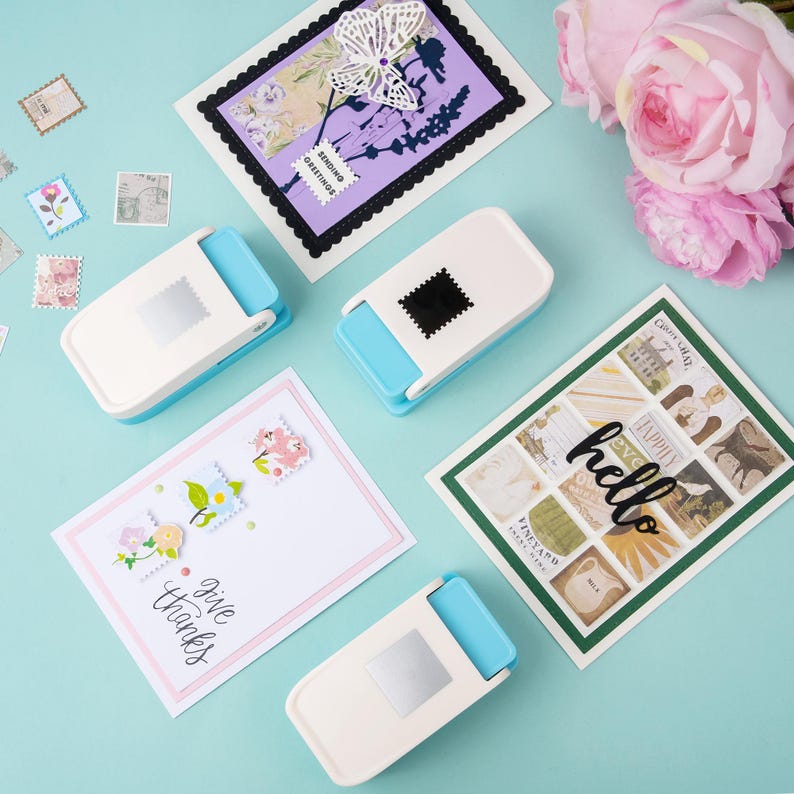 May include: A collection of handmade greeting cards and craft supplies. The cards feature floral and butterfly designs, with the words "hello" and "give thanks". Several white and blue stamp-shaped paper punches are also visible.