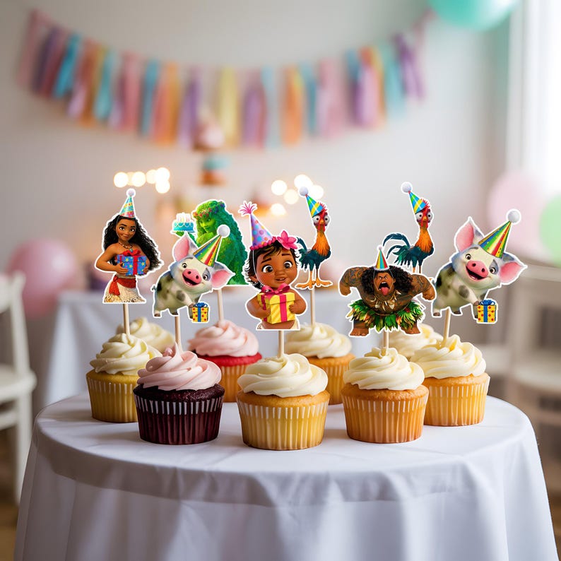 Puede incluir: Cupcakes con adornos de personajes de Moana y otros personajes de la pel&iacute;cula. Los cupcakes tienen glaseado blanco y rosa, y est&aacute;n colocados sobre un mantel blanco. Una colorida pancarta est&aacute; en el fondo.