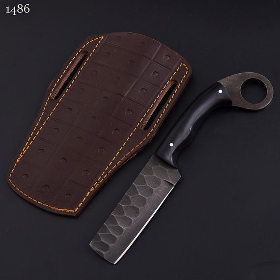 A blacksmith actually hammered a retired railroad spike into a functional bull cutter with a resin handle and leather sheath — rugged American craft you can feel.