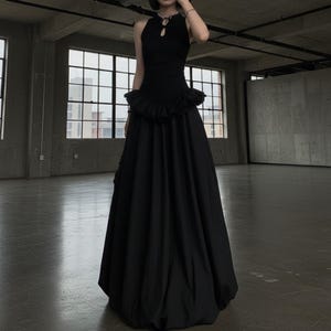 Full-length view of the black gothic maxi dress worn in a moody industrial loft setting.