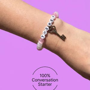 Pulseira rosa de miçangas com pingente "A CHAVE" | Bijuteria artesanal para festivais | Kandi