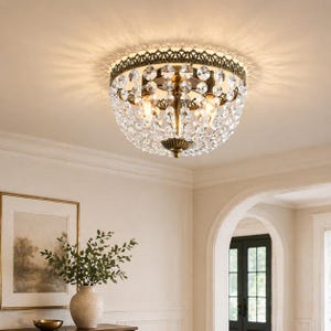 May include: A vintage-style ceiling light fixture with a bronze-colored metal frame and a dome of sparkling crystals. The light has multiple bulbs and casts a warm glow, adding a touch of elegance to any room. The fixture is mounted on a white ceiling.