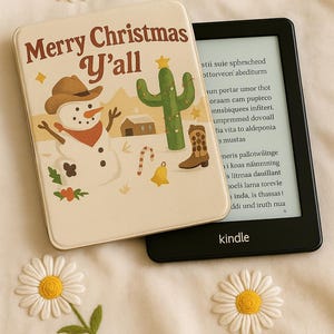 Peut inclure: Un étui crème avec le texte "Merry Christmas Y'all" et un motif de bonhomme de neige, de cactus et de botte de cowboy. Un lecteur de livre électronique Kindle noir est à côté de l'étui, avec le mot "kindle" visible. Des marguerites décoratives sont éparpillées.