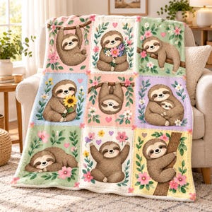 May include: A soft throw blanket featuring a grid of nine panels, each displaying a brown sloth in various poses among pink and white flowers, green leaves, and small hearts. The sloth illustrations include hanging, sitting with flowers, sleeping, and holding a baby sloth.