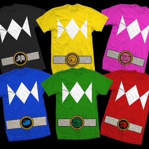 May include: Six short-sleeved t-shirts in black, yellow, pink, blue, green, and red. Each shirt features a white diamond design on the chest and a belt graphic with a circular emblem. The shirts are arranged on a black background.