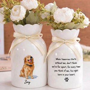 May include: Two white ceramic vases with scalloped rims and cream-colored ribbons. One vase features a golden retriever illustration with the name Zoey below it. The other vase displays the text: When tomorrow starts without me, don't think we're far apart, for every time you think of me, I'm right here in your heart, with a paw print.